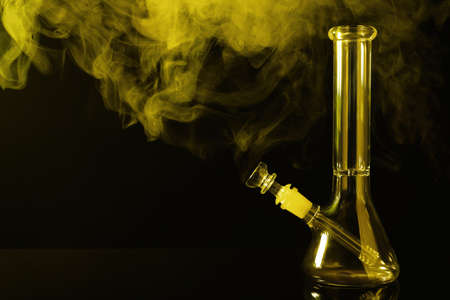 Glass bong and smoke on black background, space for text. smoking deviceの写真素材