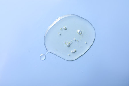 Drop of hydrophilic oil on light blue background, top viewの写真素材