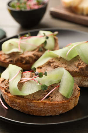Slices of bread with delicious pate, cucumber and microgreens on table, closeup