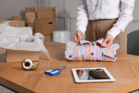 Seller packing shirt at table in office, closeup. online storeの写真素材