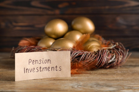 Many golden eggs and card with phrase Pension Investments on wooden table, space for textの写真素材