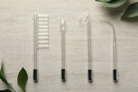 Flat lay composition with darsonval and different nozzles on white wooden table