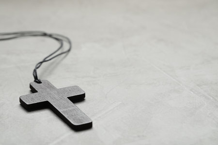 Wooden Christian cross on light gray table, closeup. Space for textの写真素材
