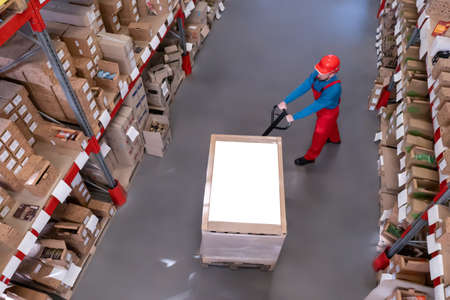 Man in hardhat working with pallet truck at warehouse, above view. logistics center