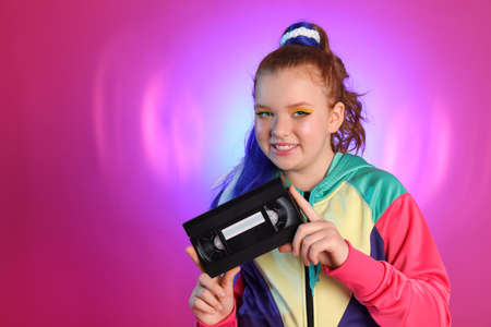 Cute indie girl with VHS cassette on violet background, space for text