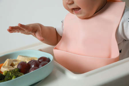 Cute little baby wearing bib while eating on white background, closeupの写真素材
