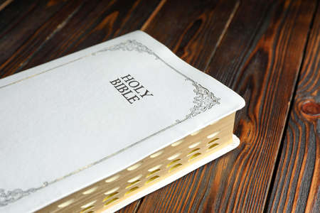 Old hardcover Bible on wooden table, closeup. religious book