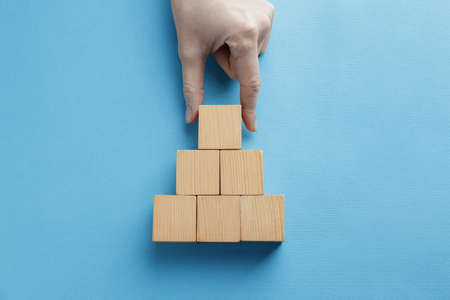 Woman arranging blank wooden cubes on light blue background, top view. Space for textの写真素材