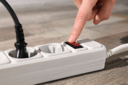 Man pressing power button of extension board on floor, closeupの写真素材