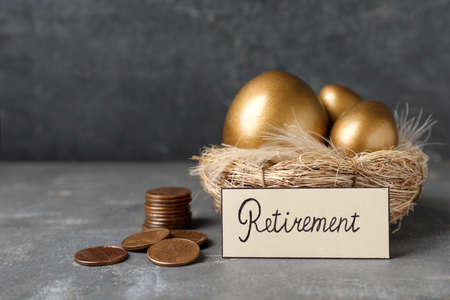 Many golden eggs, coins and card with word Retirement on gray table. pension conceptの写真素材