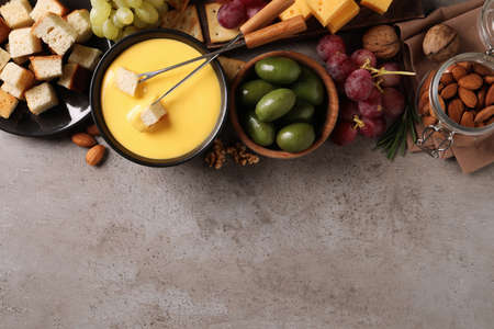 Tasty cheese fondue and snacks on gray table, flat lay. Space for textの写真素材