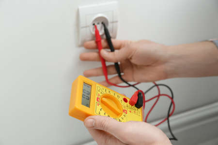 Electrician with tester checking voltage indoors, closeup