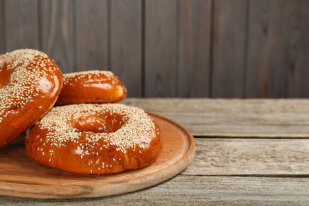 Delicious fresh bagels with sesame seeds on wooden table, closeup. Space for textの写真素材