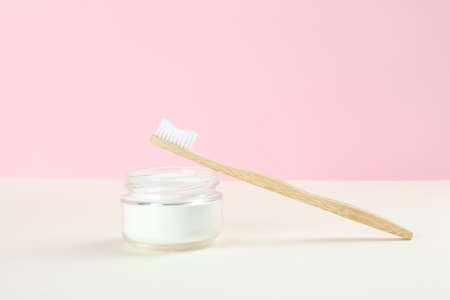 Bamboo toothbrush and bowl of baking soda on beige table against pink backgroundの写真素材