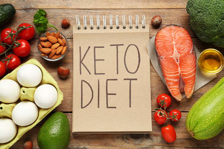 Notebook with phrase Keto Diet and different products on wooden table, flat layの写真素材