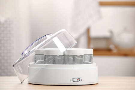 Modern yogurt maker with empty jars on table indoorsの写真素材