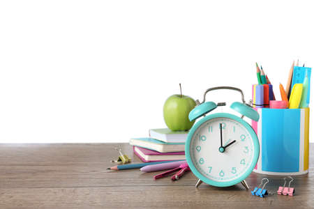 Turquoise alarm clock and different stationery on wooden table against white background, space for...