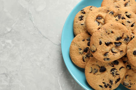 Plate with delicious chocolate chip cookies on gray marble table, top view. Space for textの写真素材