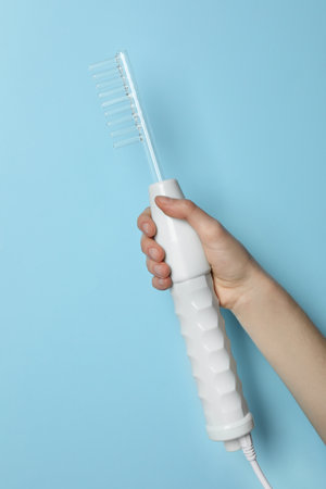 Woman with darsonval on light blue background, closeup