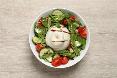 Delicious burrata salad on wooden table, top view