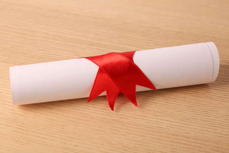 Graduation diploma tied with ribbon on wooden table