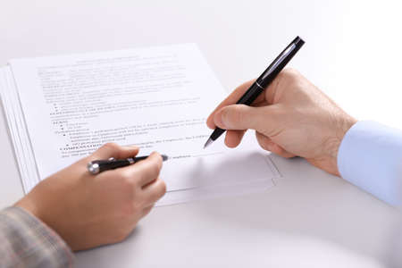 Businesspeople signing contract at white table, closeup of hands