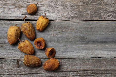 Many tasty dried persimmon fruits on wooden table, flat lay. Space for text