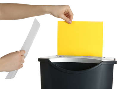 Woman destroying sheet of yellow paper with shredder on white background, closeupの写真素材