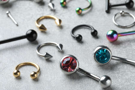 Stylish piercing jewelry on light gray table, closeup