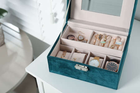 Elegant jewelry box with beautiful bijouterie and expensive wristwatches on white table in room