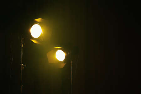 Bright yellow spotlights on dark stage, space for textの写真素材