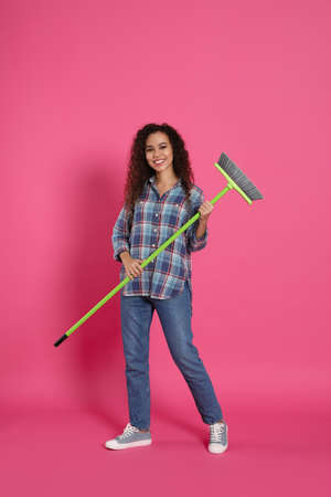 African American woman with green broom on pink backgroundの写真素材