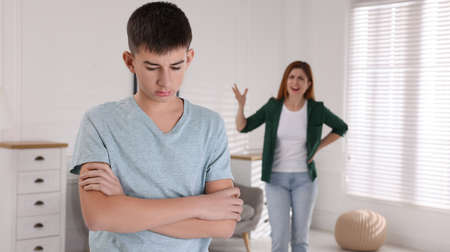Mother scolding his son at home. Teenager problemsの写真素材