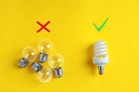 One fluorescent light bulb and simple ones on yellow background, flat lay. energy saving concept