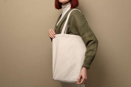 Woman with eco bag on beige background, closeup. Space for text