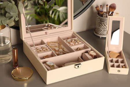 Elegant jewelry boxes with expensive wristwatches and beautiful bijouterie on gray table