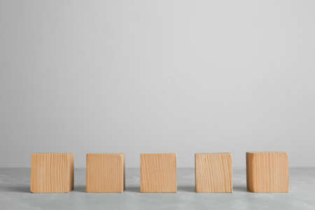 Row of blank wooden cubes on gray table against light background. Space for textの写真素材