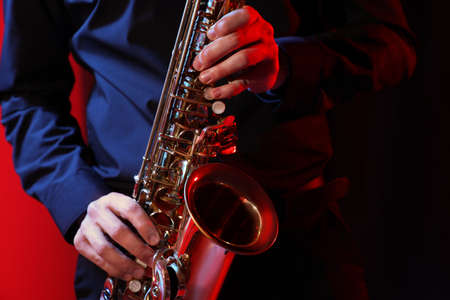 Man with saxophone on dark background, closeupの写真素材