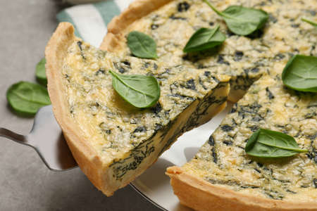 Delicious homemade spinach pie and spatula on gray table, closeup