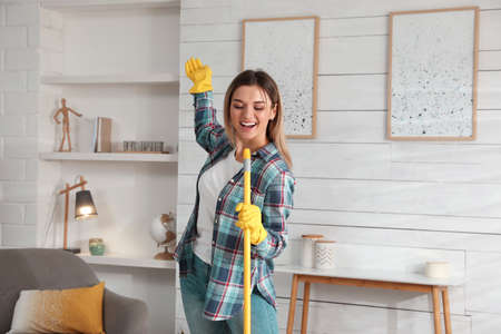 Woman with mop singing while cleaning at homeの写真素材