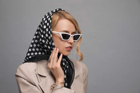 Young woman with sunglasses and stylish bandana on gray background. Space for textの写真素材