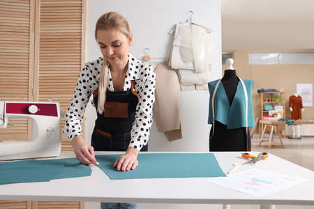 Dressmaker marking fabric with chalk in workshop