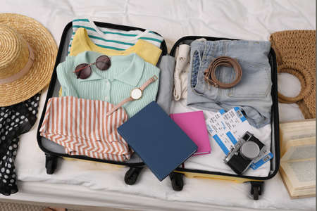 Open suitcase with clothes and accessories on bed, flat layの写真素材