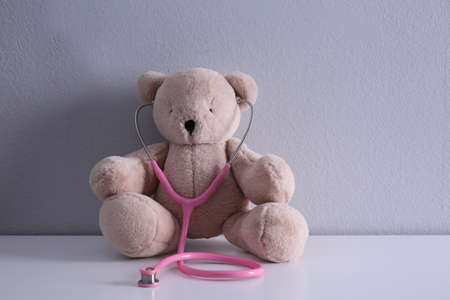 Cute teddy bear with stethoscope on white table. children's hospitalの写真素材