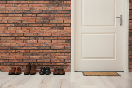 Different shoes near red brick wall in hallwayの写真素材