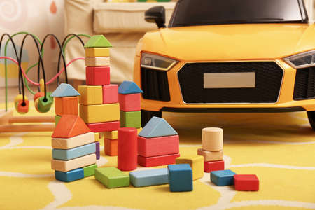 Colorful building blocks and child's electric car on floor in playroom