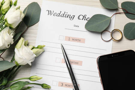 Flat lay composition with Wedding Checklist on white wooden table