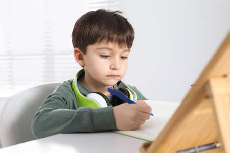Cute little boy with modern tablet studying online at home. e-learning