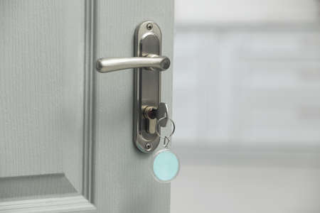 Key with fob in door lock, closeup. Space for text