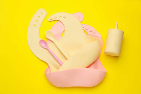Baby feeding accessories and bibs on yellow background, flat layの写真素材